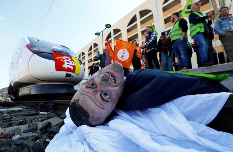 A puppet depicting French President Emmanuel Macron is installed on railway tracks by protesters to block a TGV high speed train during a demonstration at the train station after the pension reform was adopted as the French Parliament rejected two motion