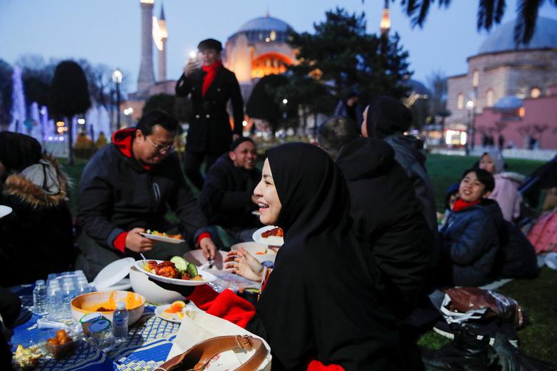 People have their iftar, or breaking fast, meal at Sultanahmet Square with the Hagia Sophia Grand Mosque in the background during the first day of Ramadan in Istanbul, Turkey, March 23, 2023.