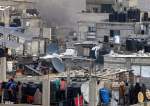 People watch from on a rooftop as Israeli bombardment strikes nearby in Rafah in the southern Gaza Strip