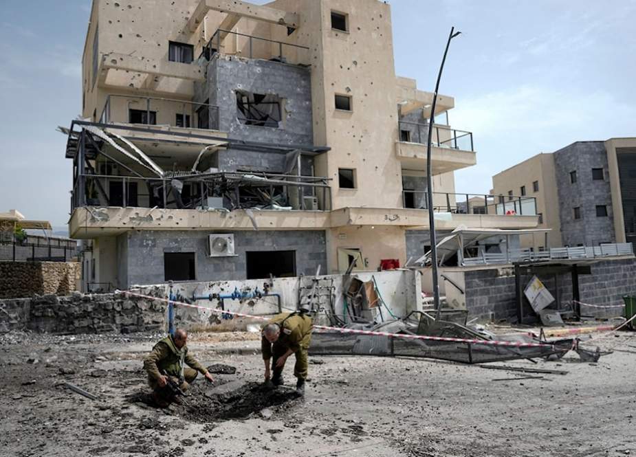 Israeli occupation forces examine the site hit by a rocket fired from Lebanon, in 